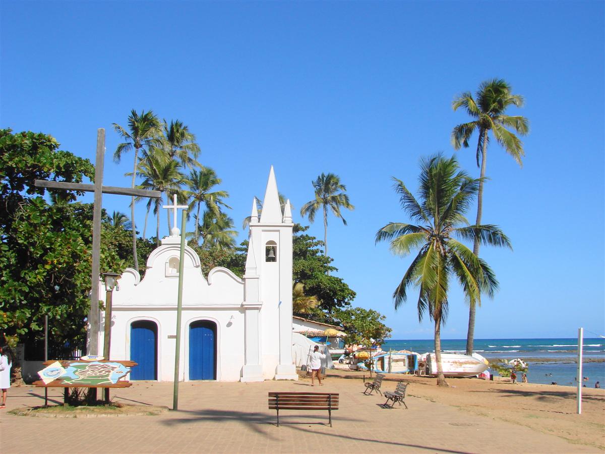 White seaside church, palm trees, and beach at Praia do Forte, Bahia.